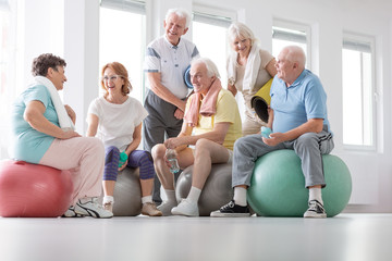 Low angle on happy elderly people on balls after gymnastic classes in the studio