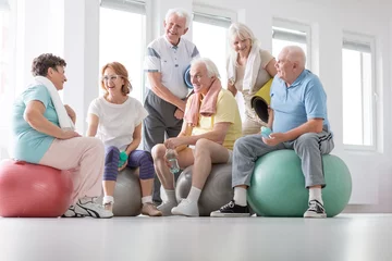 Fototapete Low angle on happy elderly people on balls after gymnastic classes in the studio © Photographee.eu