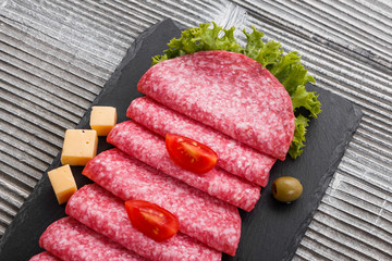 delicious sliced salami on a stone plate wooden background