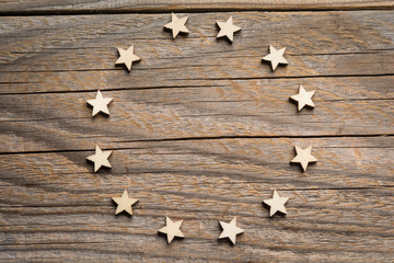 Twelve wooden craft stars form European's Union symbol on a wooden weathered surface
