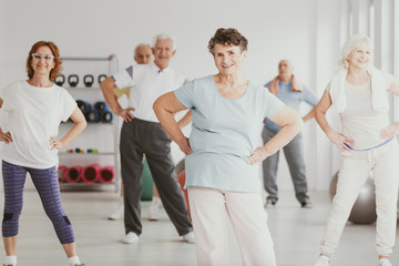 Happy senior woman holding hips during gymnastic classes for elderly people
