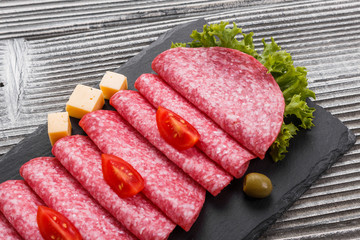 delicious sliced salami on a stone plate wooden background