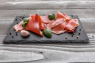 Italian prosciutto crudo or spanish jamon on a stone plate wooden background