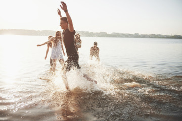 Happy friends have fun on the beach - Young people playing in open air water on summer holidays