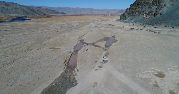 4k 60 fps Mongolia Aerial view of Altai desrt track with 4x4 driving - going through mud paddle