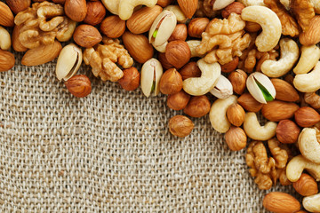 Mix of nuts lying on a background of brown cloth burlap.