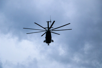 a large military helicopter hovers in the sky. A camouflaged helicopter flies at high speed.