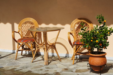 Wooden chairs and table near orange tree.