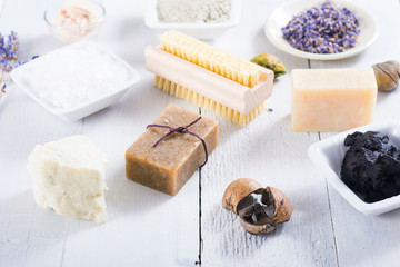 spa products: black mud and clay powder, cosmetic cream, soap, bath salt, shea butter and lavenders on white wood table background
