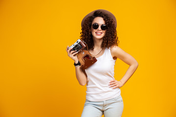 Fototapeta na wymiar Portrait of laughing young woman in eyeglasses taking pictures on retro vintage photo camera isolated on bright yellow background. People sincere emotions, lifestyle concept. Advertising area.