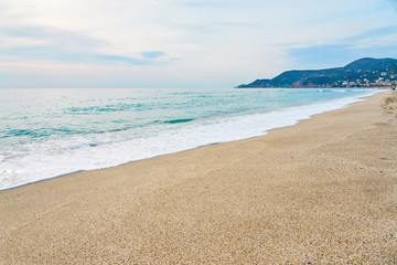 Fototapeta na wymiar Sunset at the beach, waves with foam hitting sand. 