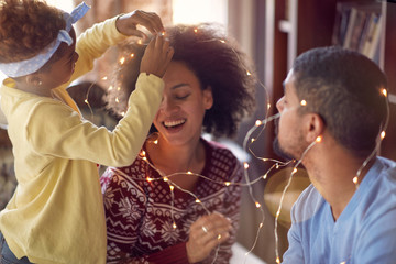 Beautiful young family enjoying their holiday time together, decorating Christmas lights .
