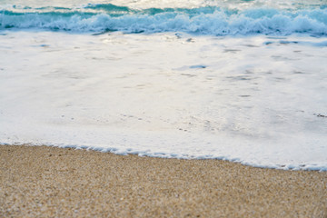 Waves with foam hitting sand on the tropical beach texture.