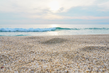 Sand on the beach close up with blurred sea and waves on a background on a sunset. 