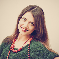 Attractive smiling trendy woman posing against white wall, image with warm vintage toning and...