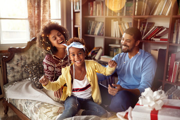 happy family – mother, father and little daughter playing together for the Christmas holidays.