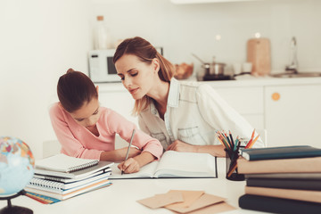 Mom Helps Daughter To Do Homework In The Kitchen.
