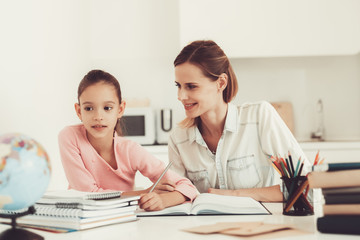 Mom Helps Daughter To Do Homework In The Kitchen.