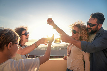 Group of friends celebrating toasting with drinks the new year. Male and female friends make toast Aas they celebrate at party. Group of people with teen laughing out loud outdoor with glasses in hand