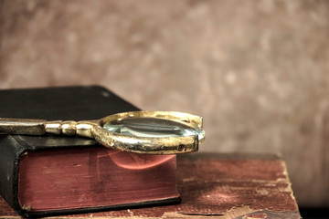 Old books and magnifier on a table. Vintage background.