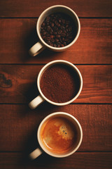 Three cups of espresso, freshly ground coffee and coffee beans on a wooden table from the top view