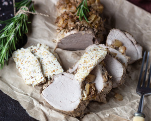 Roast pork meat with onion, garlic and rosemary served with nuts butter on brown stone table. 