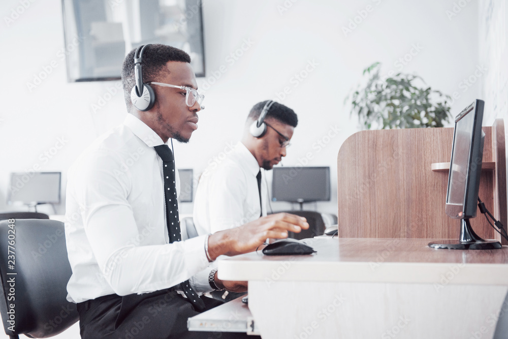 Wall mural african american customer support operator with hands-free headset working in the office