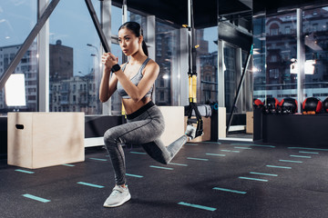 athletic asian girl stretching with resistance bands in fitness center