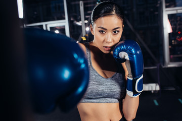 close up view of asian girl in boxing gloves training at gym
