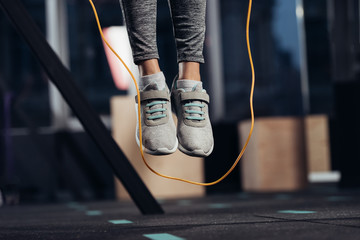 cropped view of female legs jumping with skipping rope at gym - obrazy, fototapety, plakaty