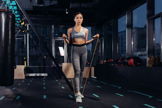 athletic girl exercising with jump rope at gym