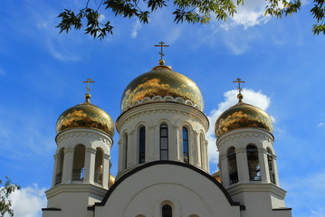 Golden domes with crosses of the white Orthodox church on the background of bright blue sky in summer day, Moscow, Russia