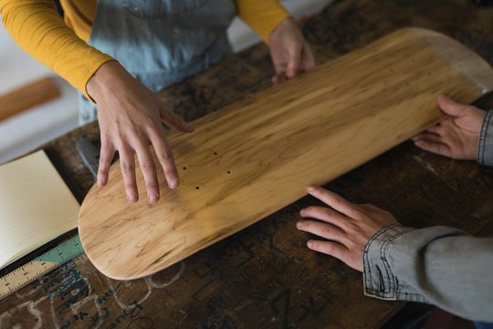 Skateboarders examining skateboard deck in workshop 