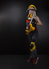 Fototapeta premium blonde girl in overalls posing with an electric saw