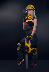Fototapeta premium blonde girl in overalls posing with an electric saw