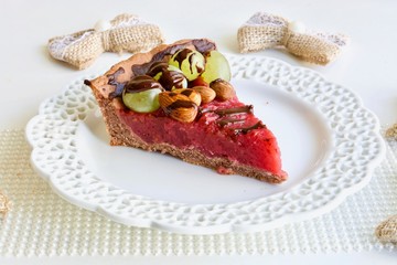 Tasty pink raspberry tart with grape and almonds on the white table.