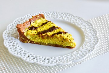 Tasty yellow lemon tart with the dark chocolate on the white table
