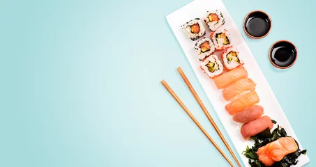 Foto op Plexiglas Sushi rolt set met zalm en tonijn op lichtblauwe achtergrond van bovenaf. © hitdelight