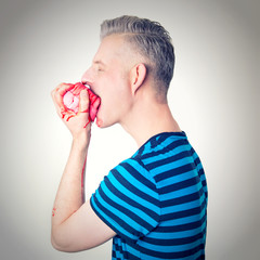 Man in blue striped shirt and short hair devouring a pink jelly pudding with red sauce.