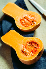 View on raw halves of butternut squash on a kitchen table. Seasonal vegetable food, still life.