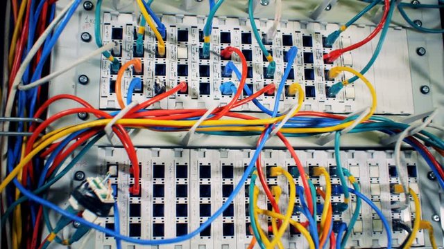 Chaos, mess with wires. Plugged multicolored cables at a data center, close up.
