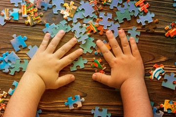 child's hands, puzzles on wooden background. logical Board game, preschool education.