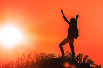 silhouette of a girl on top of a mountain against the evening sky. tourism, travel. achieving goal.