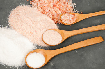 three colors of Himalayan salt with spoons on grey, concrete background