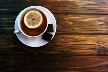 a Cup of tea with lemon, two pieces of chocolate on a wooden background. tea, drink, rest.