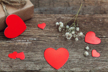 Fototapeta premium Gift box present wrapped craft paper with red hearts on rustic trendy old vintage wooden background. Christmas happy Holiday greeting card anniversary Christmas, new year, valentine day, birthday