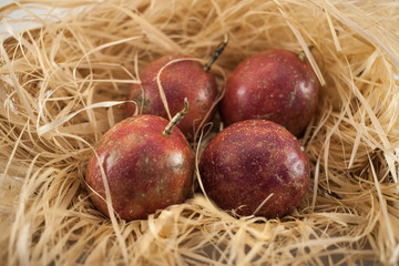 Four passion fruit isolated. Whole maracuyas on straw