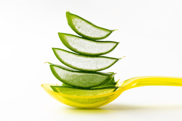 Pieces of aloe vera leaf on a yellow spoon on white background
