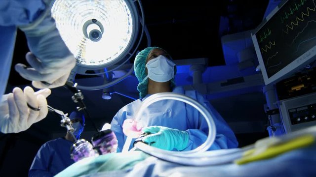 multi ethnic Medical surgical team in scrubs training in sterile operating theater using an Endoscopy to specialise in Laparoscopy surgery with camera technology 
