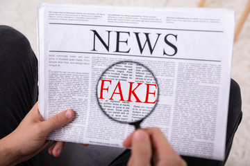 Man Examining Fake News On Newspaper